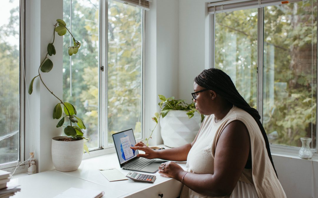 woman remote working beside a large window